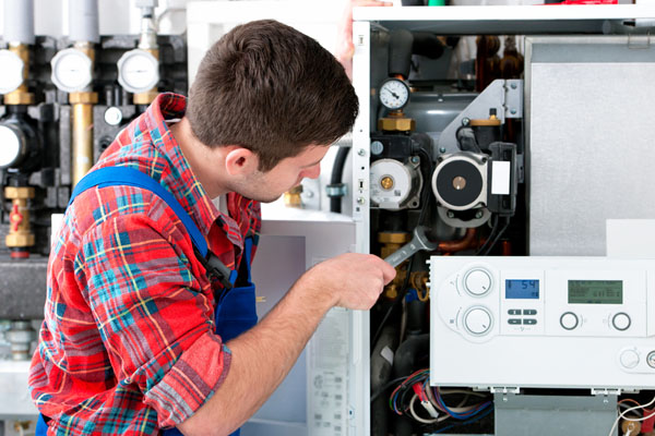 HVAC technician inspecting and repairing boiler controls in South Jordan