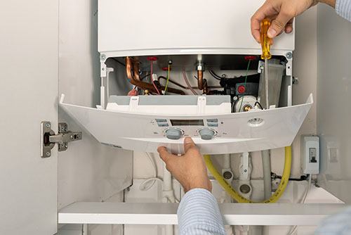 HVAC technician repairing an indoor boiler in South Jordan